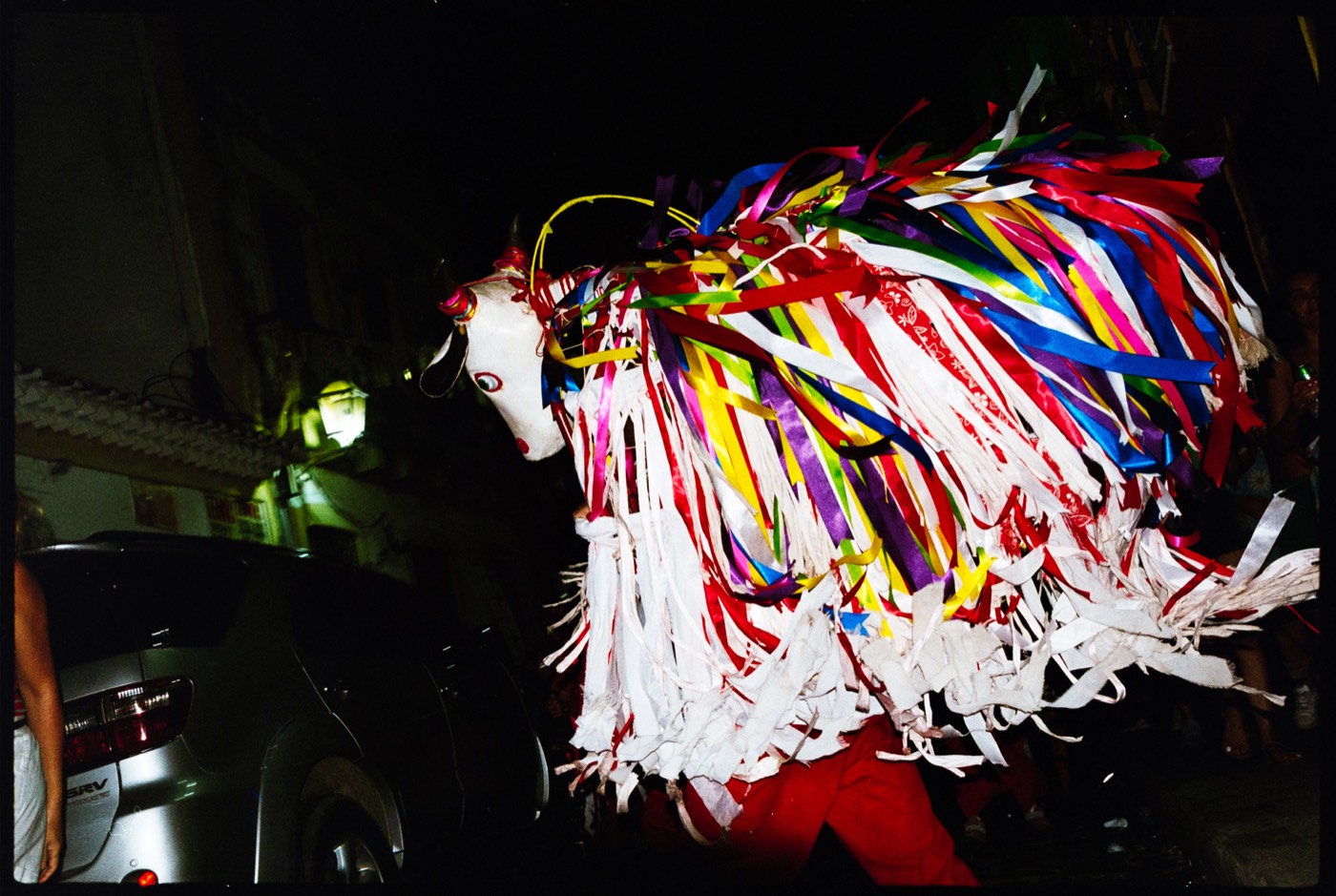 Boi de fitas coloridas na rua à noite, visto de lado